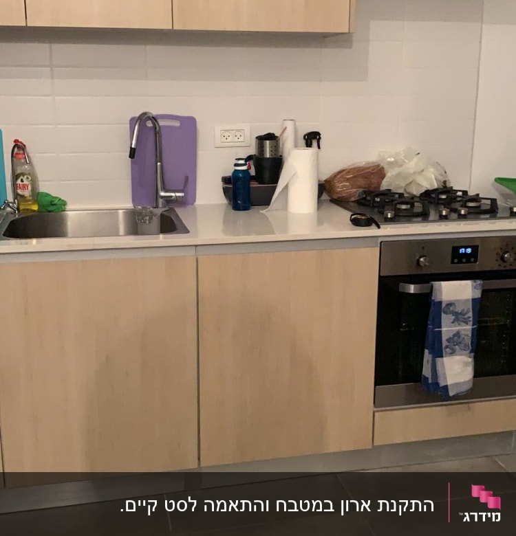 מטבח עם כיור, כיריים, מגבת, קרש חיתוך וסבון כלים